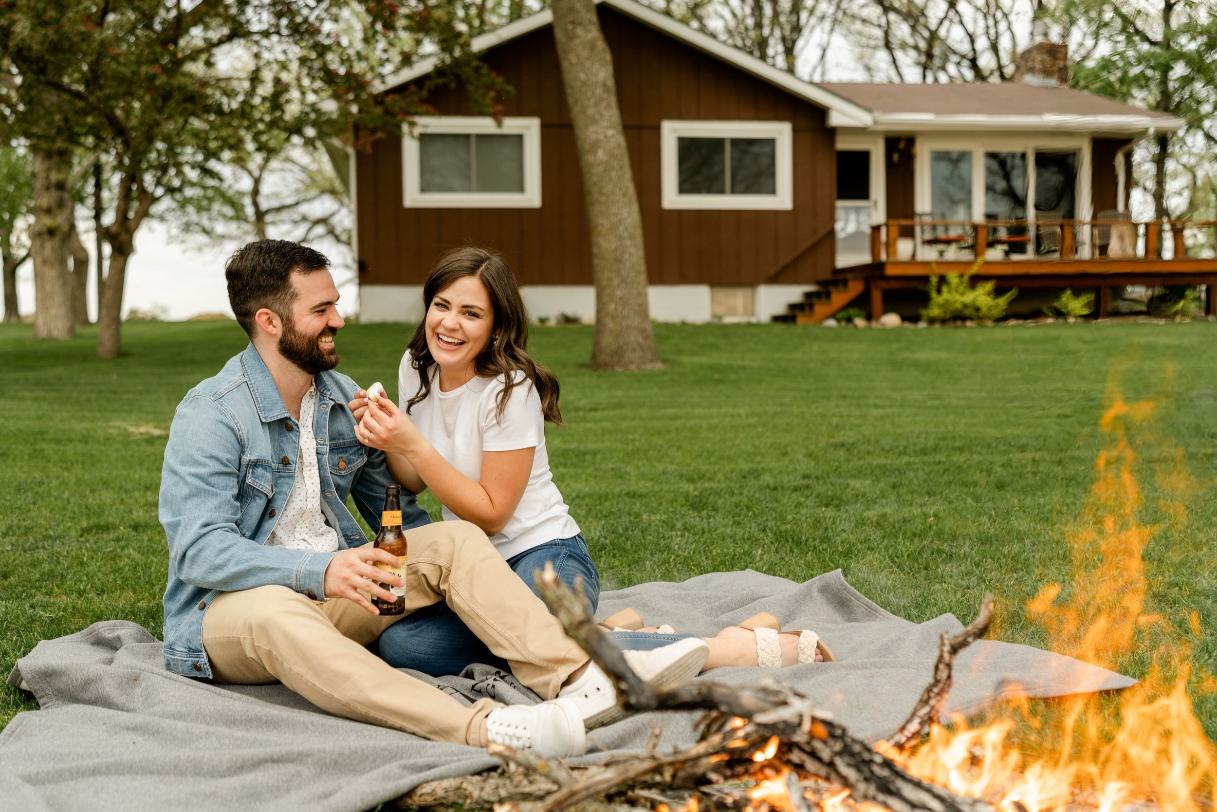 A couple roasting marshmallows over the fire at a cabin.