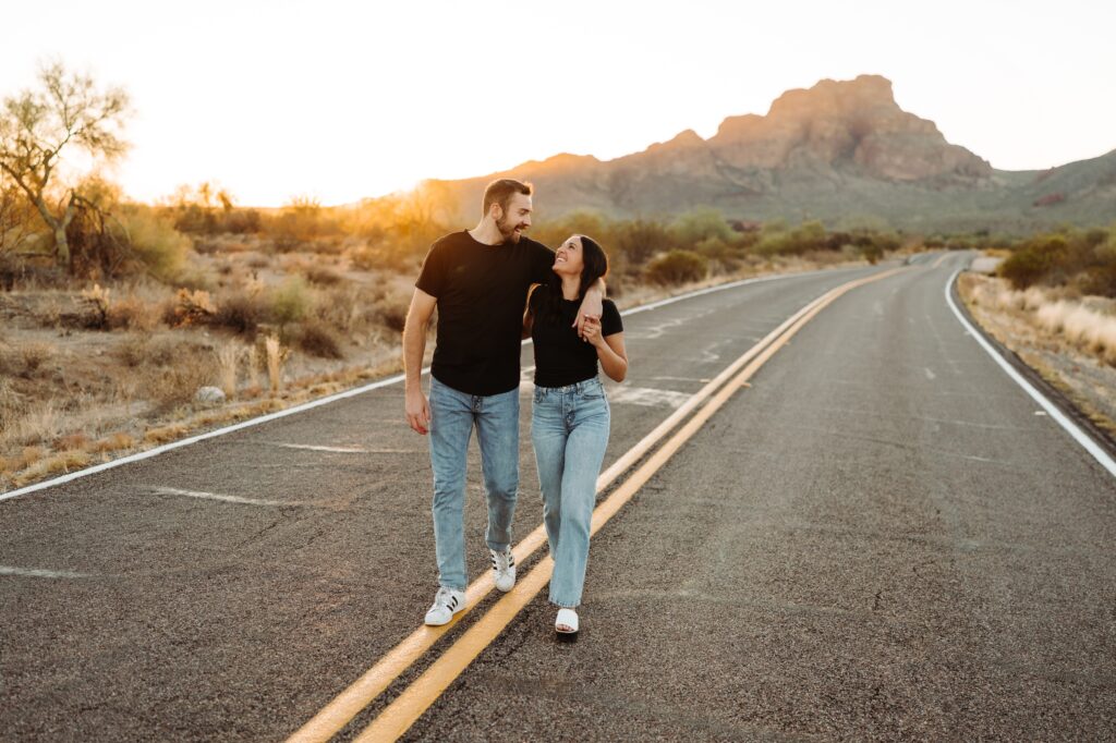 Couple walking down a road, with the guys arm around the girl.